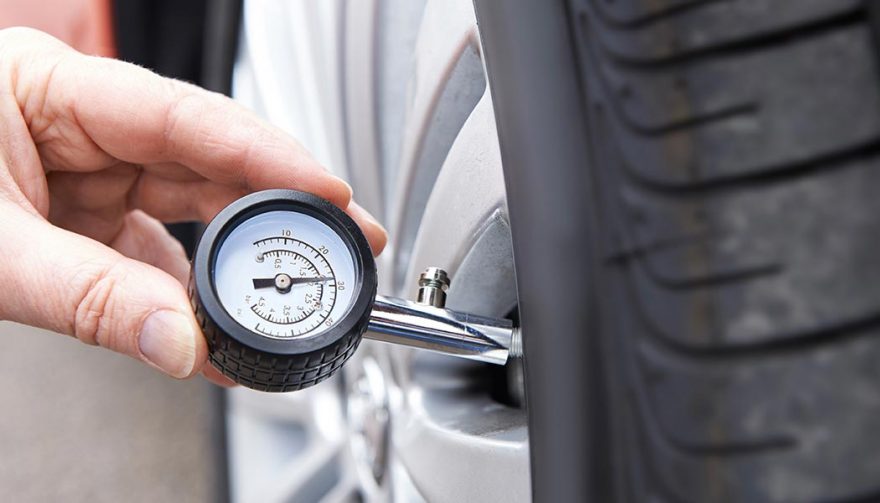 A car owner performs vehicle maintenance on the tire pressure