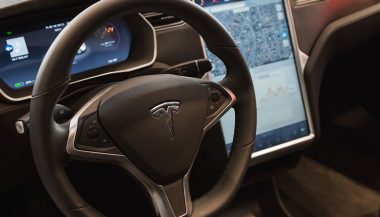 A steering wheel demonstrates the Tesla autopilot feature