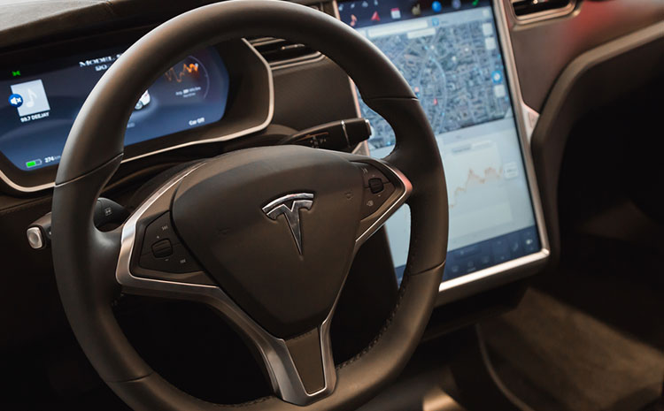 A steering wheel demonstrates the Tesla autopilot feature