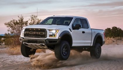 A white Ford Raptor slings some dirt off-roading