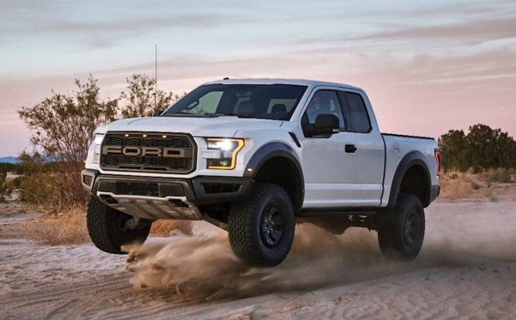 A white Ford Raptor slings some dirt off-roading