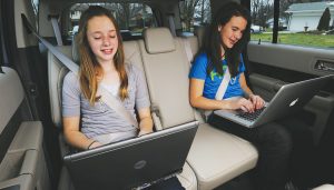 Children use a car's WiFi while on a trip.