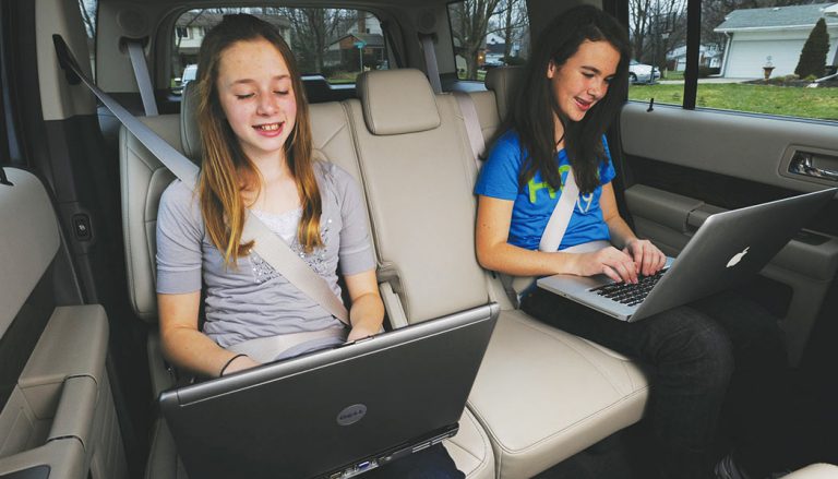 Children use a car's WiFi while on a trip.