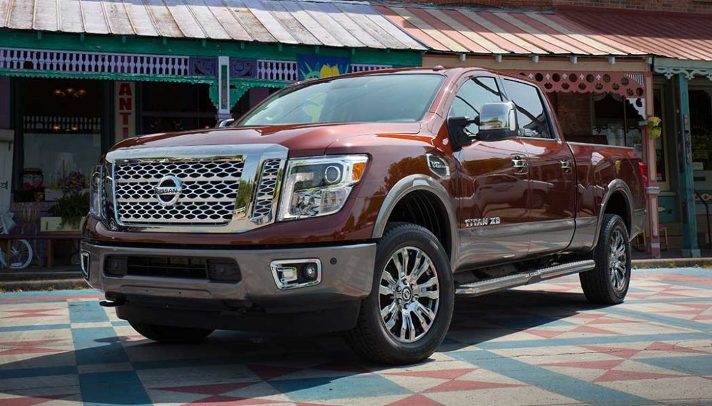 A Nissan Titan XD has large a crew cab, chrome-clad rims, big headlights and a gaping grill.