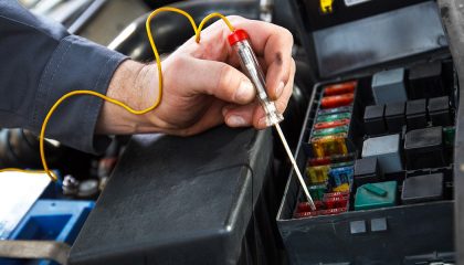 A mechanic performs car electrical repairs.