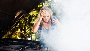 Steam pouring from under a car hood indicates an overheated engine