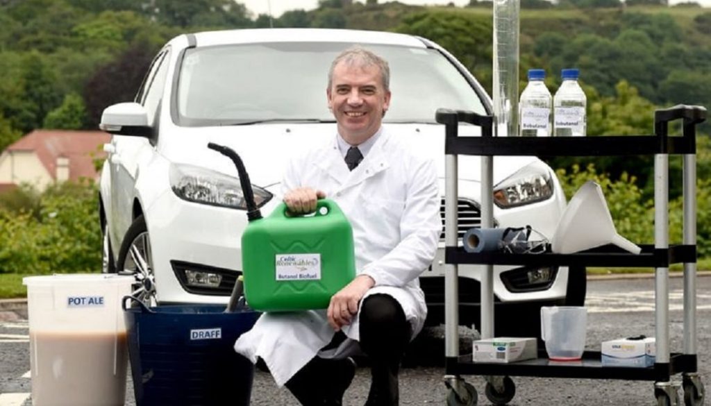 A scientist in front fo a whiskey powered car