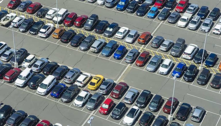 A full parking lot shows a car trying to find parking