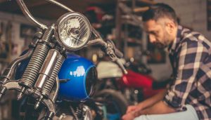 A man doing motorcycle projects in his garage