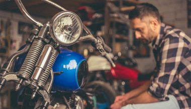 A man doing motorcycle projects in his garage