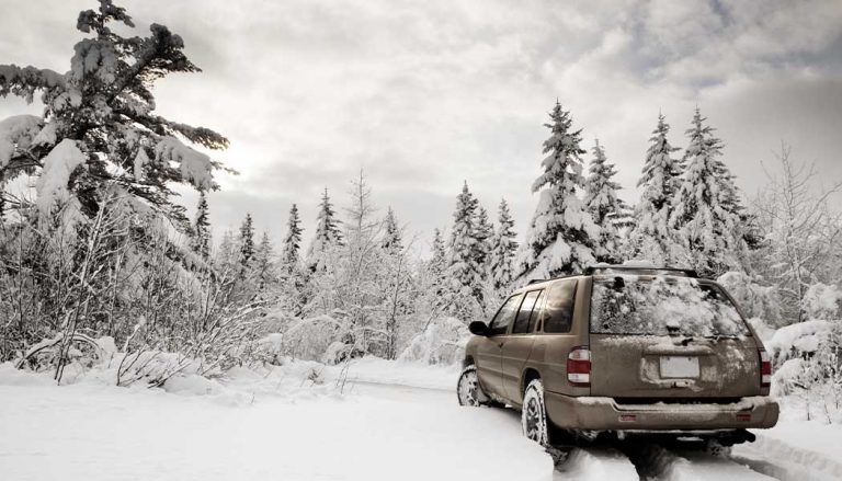 A sedan driving on a snow covered road.